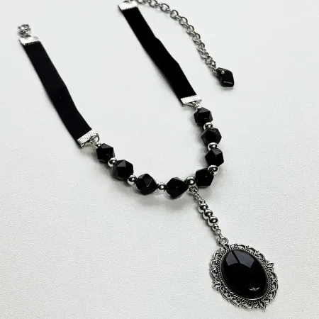 Melnā ahāta un obsidiāna kaklarota "Mēness asara" uz gaišas virsmas Ginella studijā